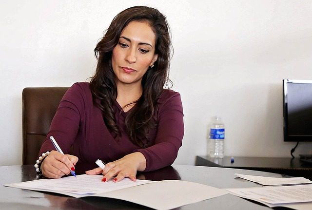 Une femme professionnelle signant des documents dans un bureau.